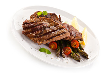Grilled beef steaks and asparagus on white background 