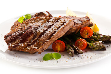 Grilled beef steaks and asparagus on white background 