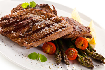 Grilled beef steaks and asparagus on white background 