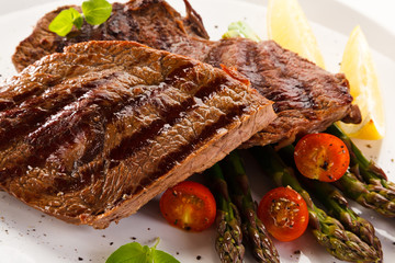 Grilled beef steaks and asparagus on white background 