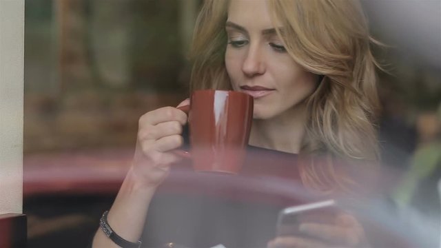 Businesswoman with smartphone drinking coffee in cafe
