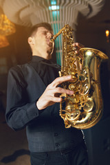 A young man in a suit playing on saxophone musical instrument