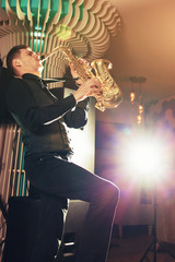 A young man in a suit playing on saxophone musical instrument