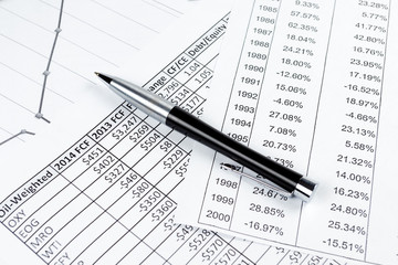 Elegant pen on financial reports, charts, papers.