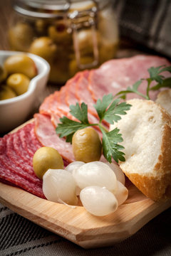 Tapas with sliced sausage, salami, olives, marinated onions, cuc