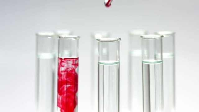 Drop red liquid in test tubes rotating on stand, blood testing
