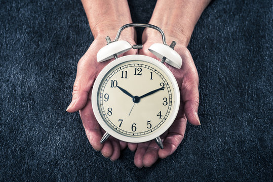 目覚まし時計を持っている高齢の女性の手 ボディーパーツ