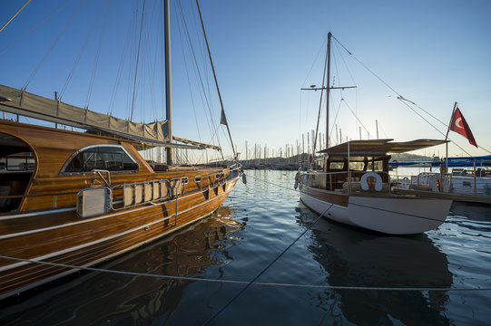 Traditional gulet sailboats moored in the marina at sunset in the tourist resort town of Bodrum, Turkey