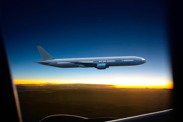 Airplane flying high above the clouds at sunset .