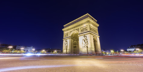 Fototapeta premium Łuk Triumfalny i zamazany ruch uliczny w nocy
