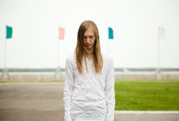 Fototapeta premium Young white man standing at the park with sad face and closed eyes. Peaceful scene