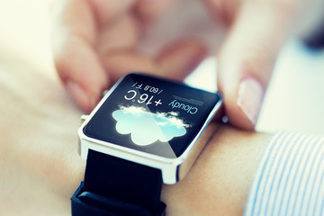 close up of hands with weather icon on smartwatch