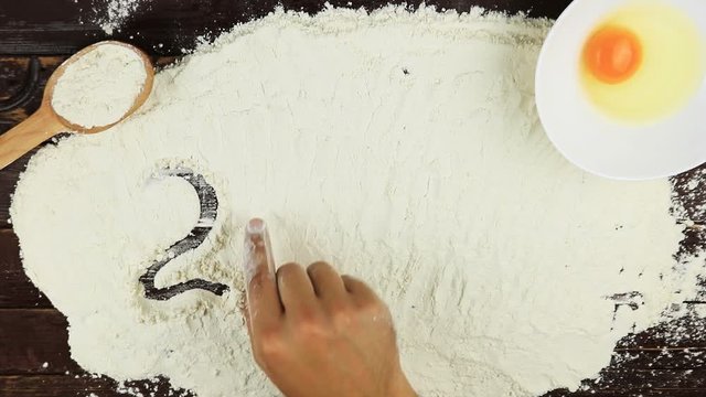 Top view Young man writes a word number 2017 on white flour at wooden desk from above.