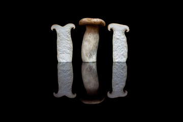 Three upright king oyster mushrooms, one whole and two halved is