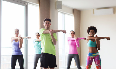 Fototapeta premium group of smiling people stretching in gym