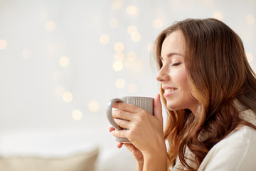 happy woman with cup of tea or coffee at home