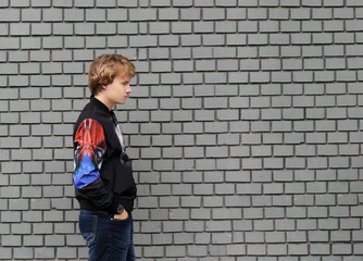 Fototapeta na wymiar Portrait of attractive teenage boy standing in front of a brick wall.