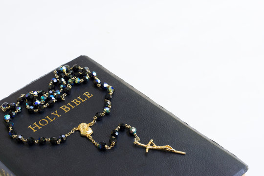 Holy bible with rosary beads on white background