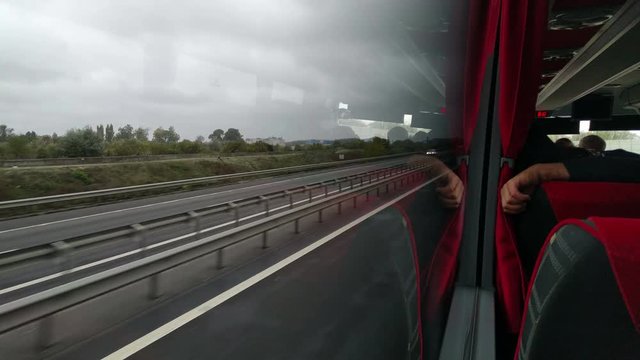 Shaky footage from inside a bus traveling on a highway, on a rainy day.