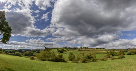 Fototapeta na wymiar thick clouds on green fall countryside, Germany