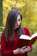 Obraz premium Portrait of beautiful young brunette girl reading a book in the