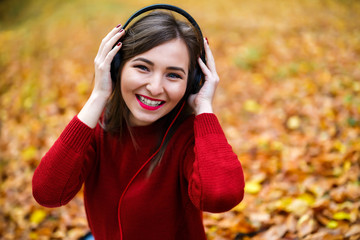 Young caucasian brunette woman with headphones outdoors on autum