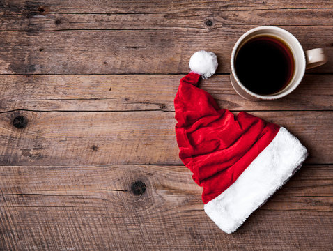 Cup of coffee and Santas hat on a wooden background, celebration