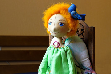 Angel with ginger hair green embroidered patterned shirt and a blue bird in the hand. Textile handmade doll.