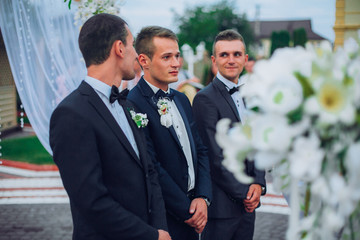 Groomsmen standing on the wedding ceremony outdoors