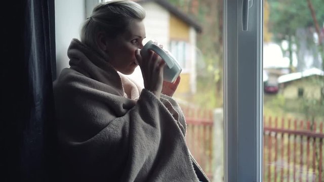 lonely depressed woman sitting on window sill