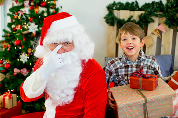 Santa Claus and cute boy getting ready for Christmas