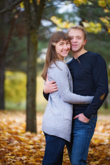 Young happy couple posing in autumn park