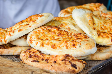 Georgian traditional dish khachapuri, pastry flat cake cheese-filled bread fried on the grill, BBQ. Fresh hot tasty street food in the market. Cooking food. Preparation dish of Middle Eastern cuisine.