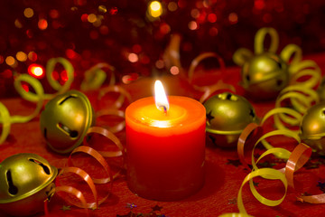 Christmas and New Year`s festive evening burning candle bokeh image. Greeting card  lights Background concept with holiday tinsel,jingles bells, twisted ribbons and copyspace place for text or logo.