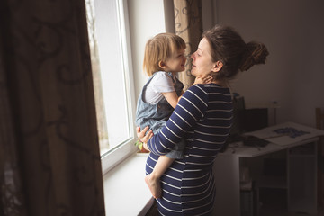 young pregnant mother and son reading a book on sofa, lifestyle,