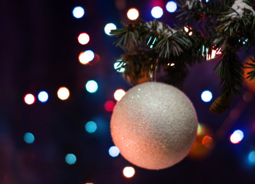 Christmas and New Year`s bokeh image. White ball toy decorations on tree, fir cones and tree branches.  Greeting card blue Background concept with holiday tinsel with copyspace place for text or logo.