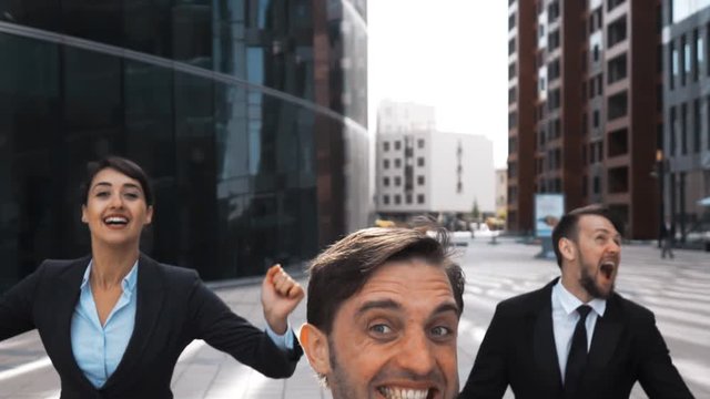 Slow motion. Three confident attractive Businesspeople in formal suit and tie exult and jump with happiness smiling. Flying high in sky levitation emotions. They looks happy of winning deal. Stabicam.