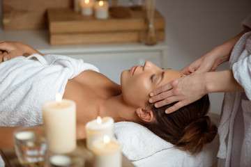 Fototapeta na wymiar Young beautiful girl having face massage relaxing in spa salon.