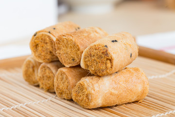 Crispy roll with dried shredded pork on a wood dish.