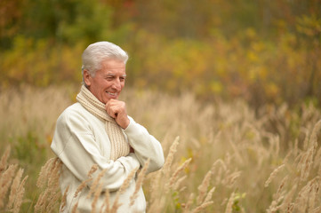 Fototapeta na wymiar Smiling elderly man in autumn park