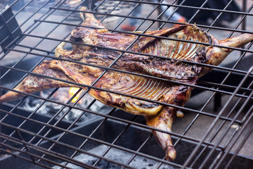 Appetizing grilled lamb on the spit. Roasted pig on traditional barbecue. Roasting barbecue is...