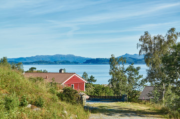 Fototapeta na wymiar Red summer cottage among the rocks, fjord