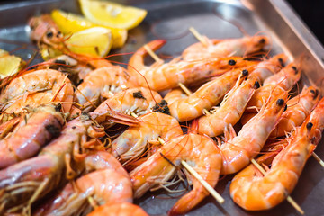 Classic tiger shrimp skewers. Shrimps sriracha kebabs with lemon for dinner. Delicious prawn spit prepared on grill. Extreme close up of appetizing grilled queen prawn on the tray.