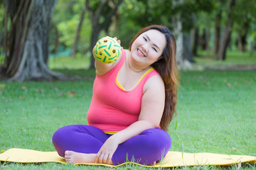 Beautiful fat woman playing with sepak takraw ball on the mat.