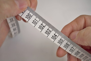 Two male hands holding a tape measure (measuring length in centimeters and meters) 