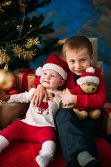 Obraz na płótnie Canvas Portrait of happy children with Christmas gift boxes and decorations. Two kids having fun at home