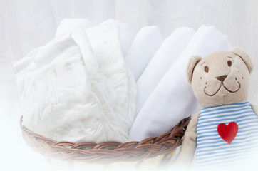 Set of diapers for newborn in basket with love bear toy. 