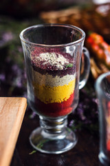 Decorative glass filled with layers of colorful spices. Close up assorted fresh condiments.