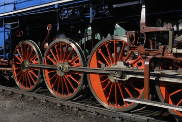 Fototapeta na wymiar Steam locomotive wheels and rods closeup. Detail of mechanical parts, wheels and equipment of the train. 