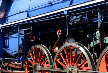 Steam locomotive wheels and rods closeup. Detail of mechanical parts, wheels and equipment of the train.
